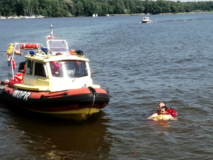 Strażak PSP holuje osobę do łodzi WOPR-u
